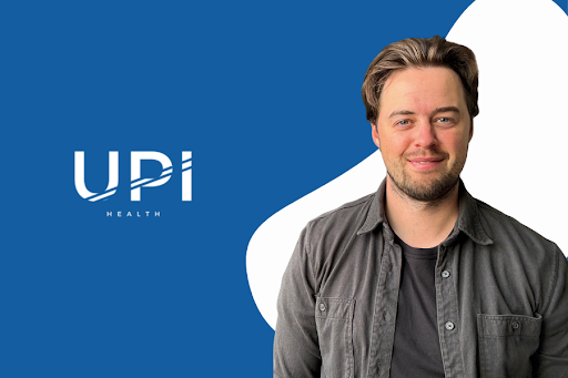 A headshot of a smiling man with light brown hair and a beard, wearing a dark grey shirt. He is positioned on the right side of the image, looking directly at the viewer. To his left, on a blue background, is the white logo for 