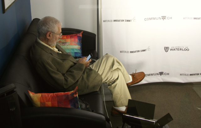Steve Blank sitting on a couch looking at their phone and away from camera