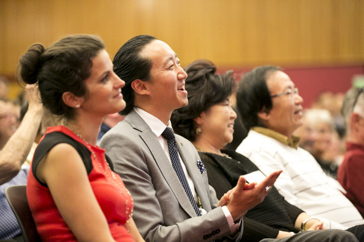 A group of people sitting in an audience watching a presentation.