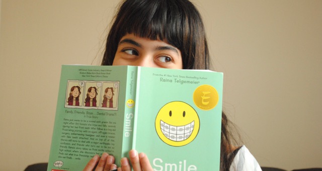 Young girl poses for a photo holding a book