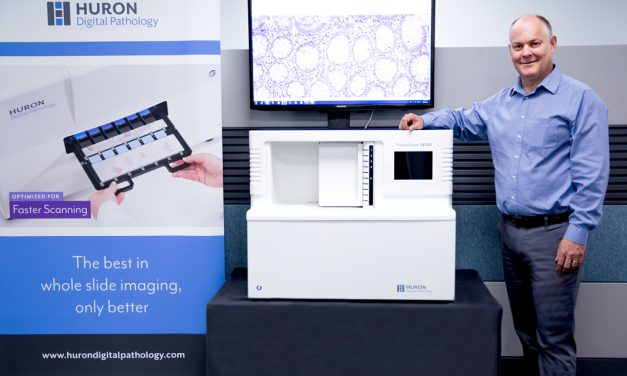 Patrick Myles, Huron Digital Pathology CEO, with one of his company’s digital scanners and company banners