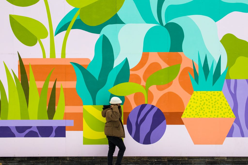 Anthony Ramsay walks in front of a Stephanie Scott mural depicting plants