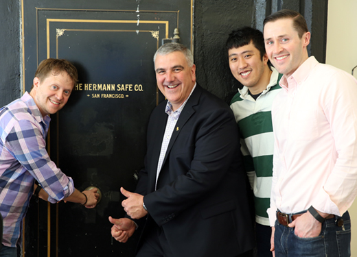 4 people are pictured on front of an old vault that says "The Hermann Safe Co. San Francisco"